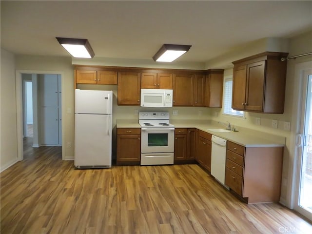 kitchen featuring a sink, light countertops, white appliances, and light wood-style flooring