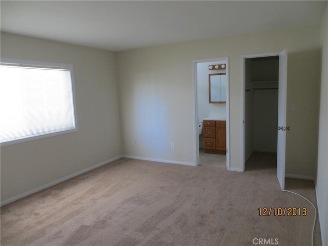 unfurnished bedroom with light colored carpet, baseboards, a spacious closet, and a closet