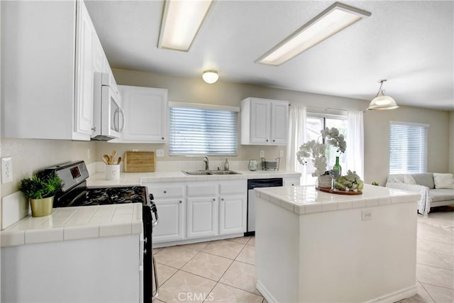kitchen with tile countertops, stainless steel gas range oven, a sink, white microwave, and dishwashing machine