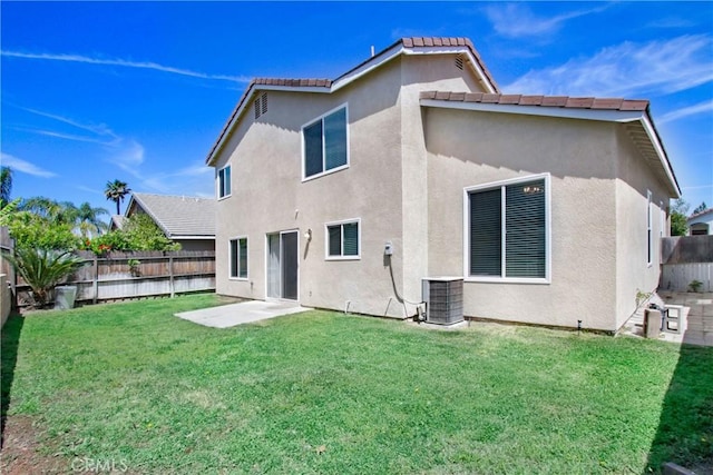 back of house with a lawn, central AC, a fenced backyard, and stucco siding