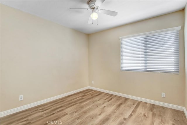 empty room featuring a ceiling fan, baseboards, and light wood-type flooring