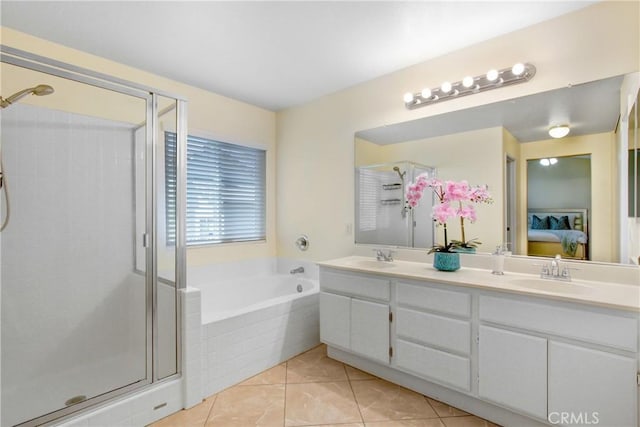 ensuite bathroom with connected bathroom, a sink, tile patterned floors, a shower stall, and a garden tub