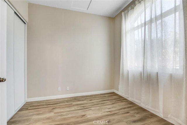 unfurnished bedroom featuring baseboards, light wood-style flooring, and a closet