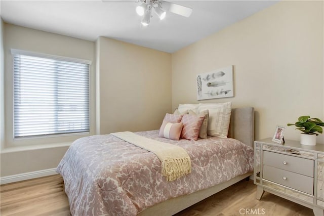 bedroom with baseboards, multiple windows, and light wood finished floors
