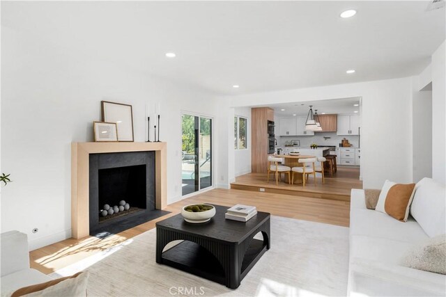 24705 Queens Ct, Laguna Niguel, CA 92677 - living area with a fireplace with flush hearth, light wood-style floors, recessed lighting, and baseboards