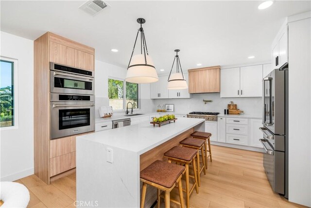 24705 Queens Ct, Laguna Niguel, CA 92677 - kitchen with appliances with stainless steel finishes, a sink, a breakfast bar, light wood-style floors, and recessed lighting