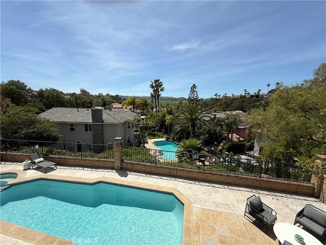 view of swimming pool featuring a patio, a pool with connected hot tub, and fence