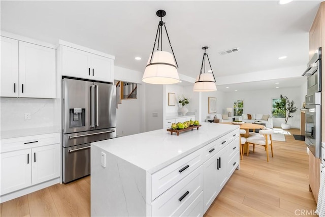 kitchen featuring a kitchen island, light countertops, open floor plan, stainless steel appliances, and recessed lighting