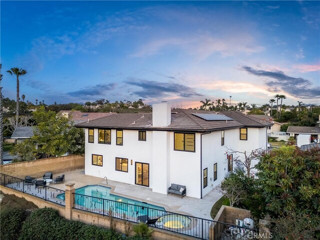 24705 Queens Ct, Laguna Niguel, CA 92677 - back of house at dusk with a patio, roof mounted solar panels, a fenced backyard, and stucco siding