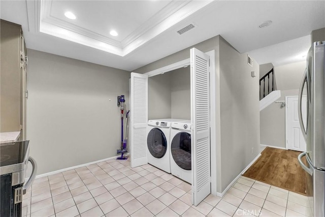 clothes washing area with laundry area, visible vents, washing machine and dryer, baseboards, and light tile patterned floors