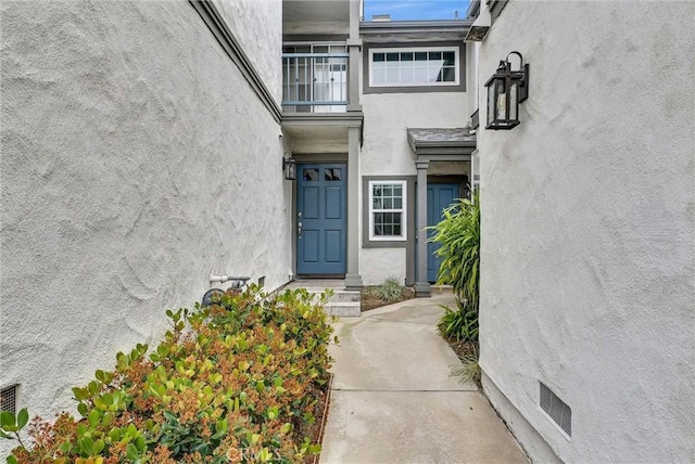 property entrance with visible vents and stucco siding