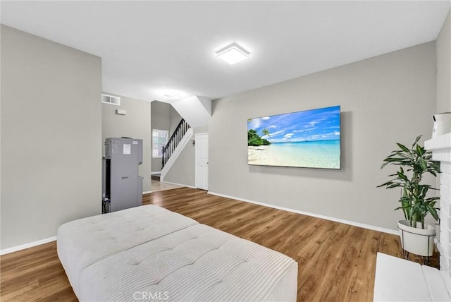 bedroom with baseboards, visible vents, and wood finished floors