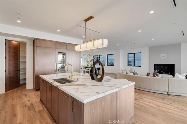 932 9th St, Manhattan Beach, CA 90266 - kitchen with a sink, a center island with sink, light wood-style flooring, recessed lighting, and light stone countertops