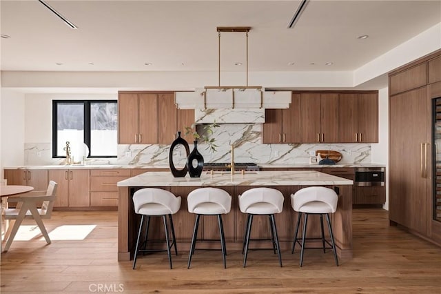 932 9th St, Manhattan Beach, CA 90266 - kitchen with backsplash, a center island with sink, light wood finished floors, and modern cabinets