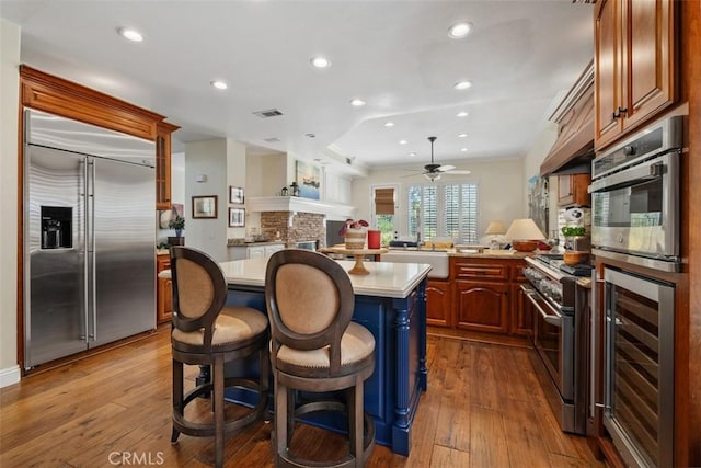 kitchen with ceiling fan, visible vents, high end appliances, light countertops, and wine cooler