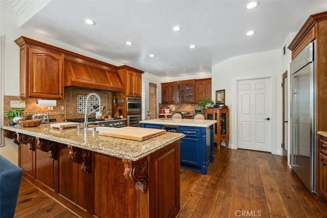 kitchen featuring dark wood finished floors, appliances with stainless steel finishes, custom range hood, and a peninsula