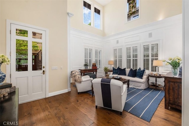 living room featuring baseboards, dark wood-style floors, and a towering ceiling