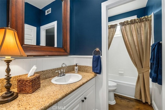 bathroom with visible vents, shower / tub combo with curtain, vanity, wood finished floors, and toilet