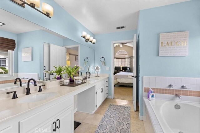 ensuite bathroom with double vanity, a sink, a bath, and visible vents