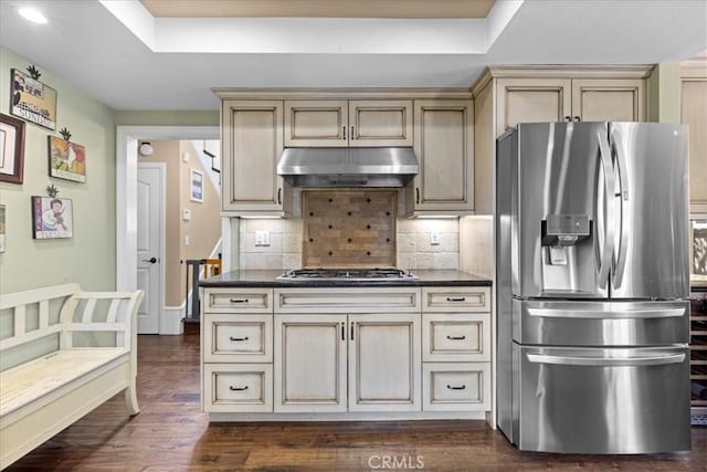 kitchen featuring a raised ceiling, under cabinet range hood, cream cabinetry, and stainless steel appliances