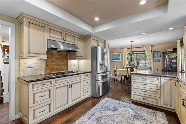kitchen with appliances with stainless steel finishes, under cabinet range hood, dark wood-type flooring, and cream cabinetry
