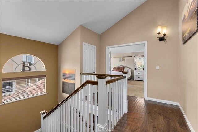hallway featuring baseboards, an upstairs landing, wood finished floors, and lofted ceiling