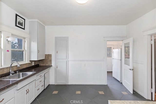 4643 Victoria Ave, Riverside, CA 92507 - kitchen with dark countertops, a sink, dark tile patterned flooring, freestanding refrigerator, and white cabinetry
