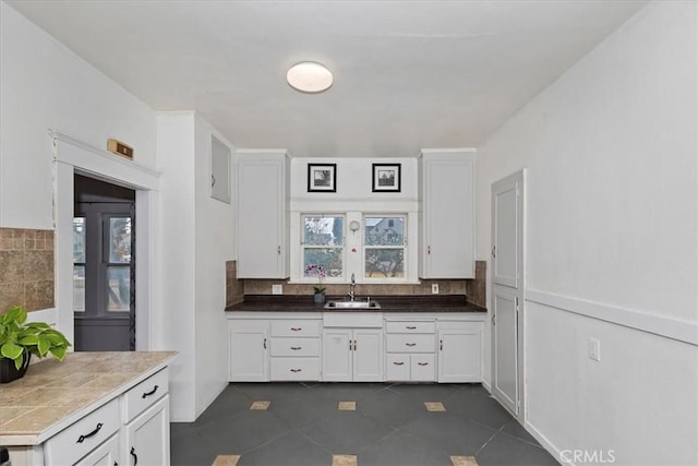 4643 Victoria Ave, Riverside, CA 92507 - kitchen featuring dark tile patterned floors, a sink, white cabinetry, and decorative backsplash