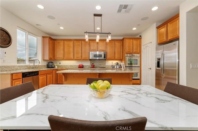 kitchen with a breakfast bar area, visible vents, appliances with stainless steel finishes, a center island, and a sink