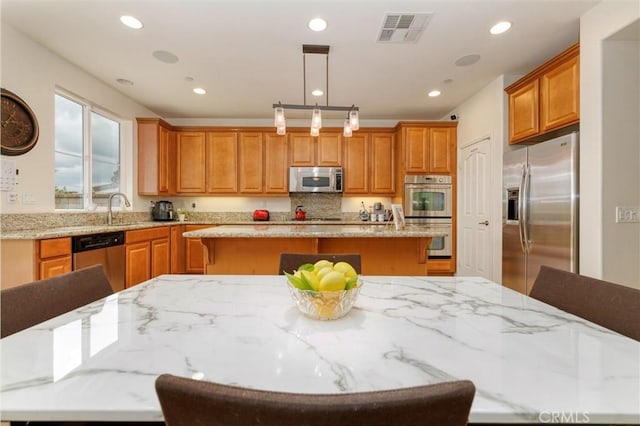 22620 Dragonfly Ct, Saugus, CA 91350 - kitchen featuring appliances with stainless steel finishes, a center island, a kitchen bar, recessed lighting, and light stone countertops