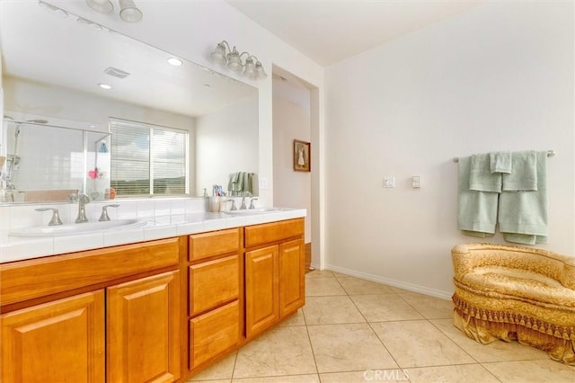 full bathroom featuring double vanity, a sink, tile patterned flooring, and a stall shower