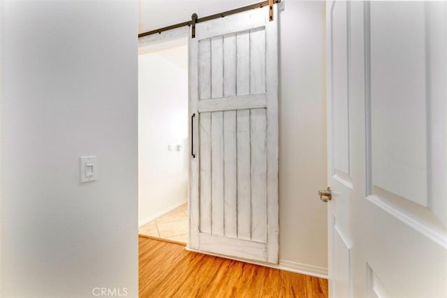 room details featuring baseboards, a barn door, and wood finished floors