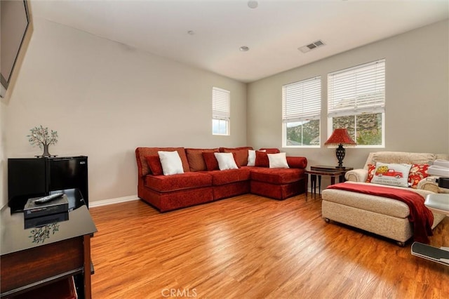 living room featuring visible vents, light wood finished floors, and baseboards