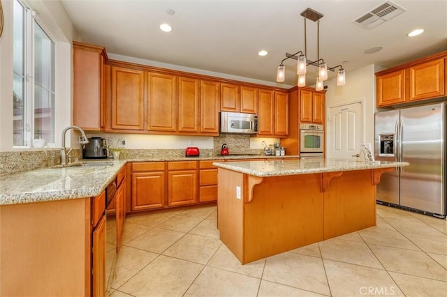 22620 Dragonfly Ct, Saugus, CA 91350 - kitchen with stainless steel appliances, a center island, a kitchen breakfast bar, light stone countertops, and light tile patterned floors