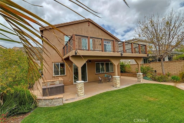 back of house featuring stucco siding, a yard, a balcony, and fence