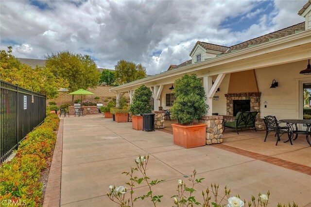 view of patio / terrace featuring an outdoor stone fireplace, fence, and outdoor dining area
