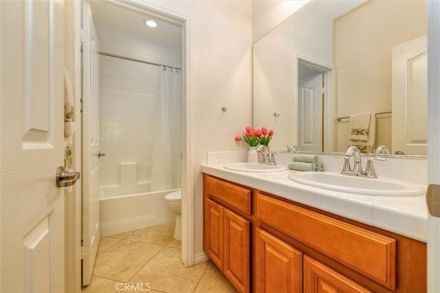 bathroom with double vanity, a sink, tile patterned floors, and toilet