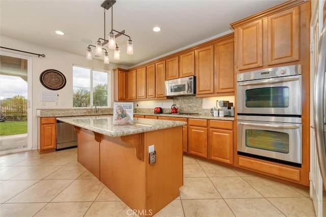 kitchen with a kitchen island, a kitchen breakfast bar, light stone counters, light tile patterned floors, and stainless steel appliances