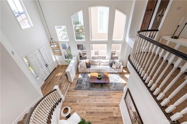 living area featuring stairway, baseboards, wood finished floors, and a towering ceiling