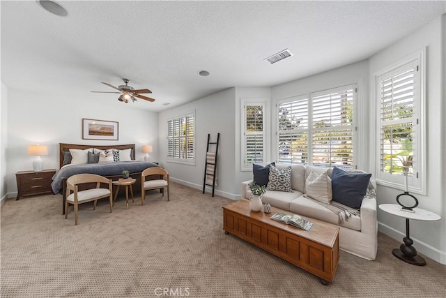 carpeted bedroom featuring baseboards, ceiling fan, a textured ceiling, and visible vents