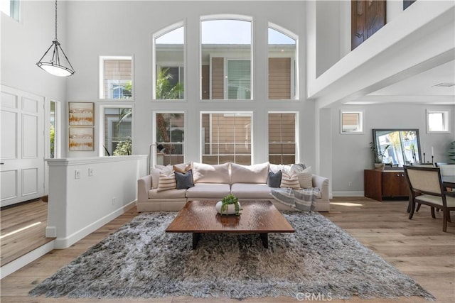 living area with baseboards, a towering ceiling, wood finished floors, and visible vents