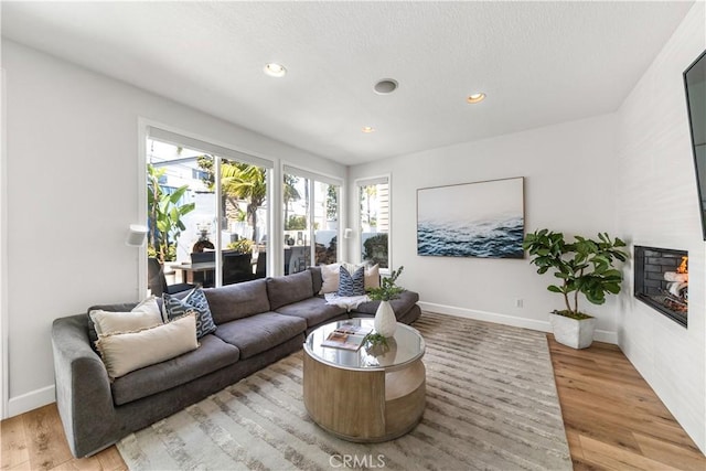 living room featuring recessed lighting, baseboards, and light wood-style floors