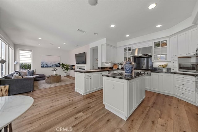 kitchen featuring visible vents, a kitchen island, dark countertops, open floor plan, and under cabinet range hood