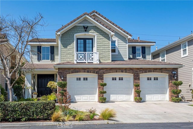 view of front of property featuring brick siding, a garage, concrete driveway, a balcony, and a tiled roof