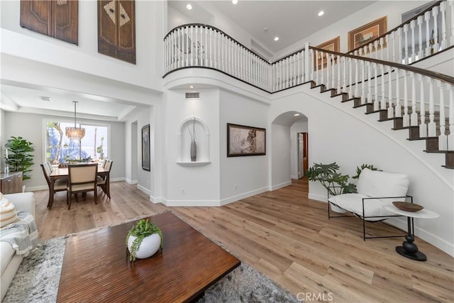 living room with stairs, arched walkways, baseboards, and light wood-style floors