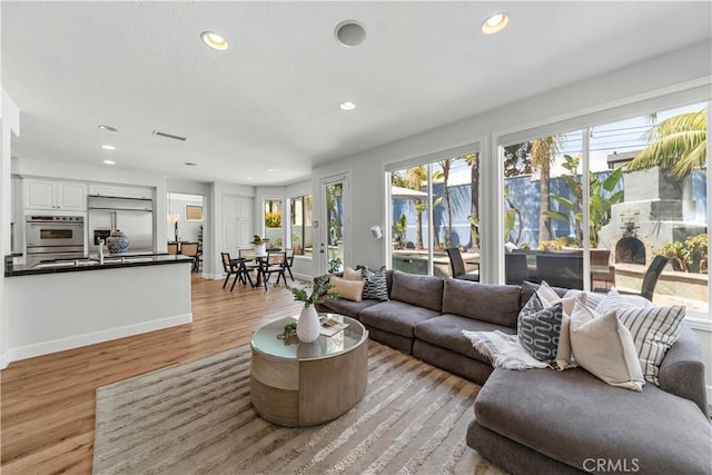 living area featuring light wood-type flooring, recessed lighting, and baseboards