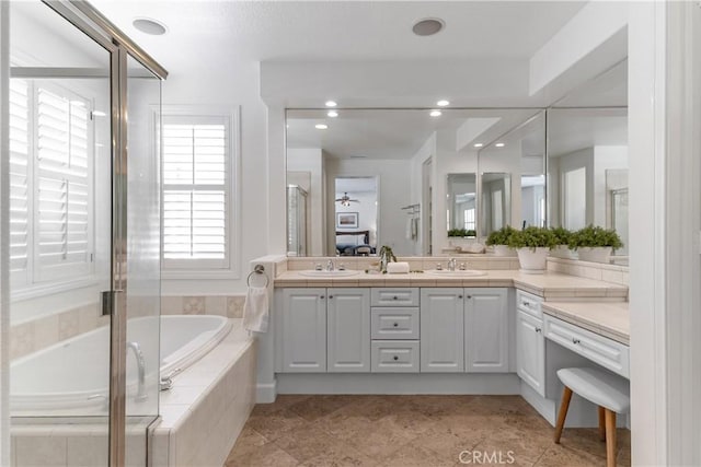 bathroom with double vanity, a sink, a garden tub, and recessed lighting