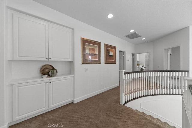 corridor featuring visible vents, baseboards, dark colored carpet, recessed lighting, and an upstairs landing