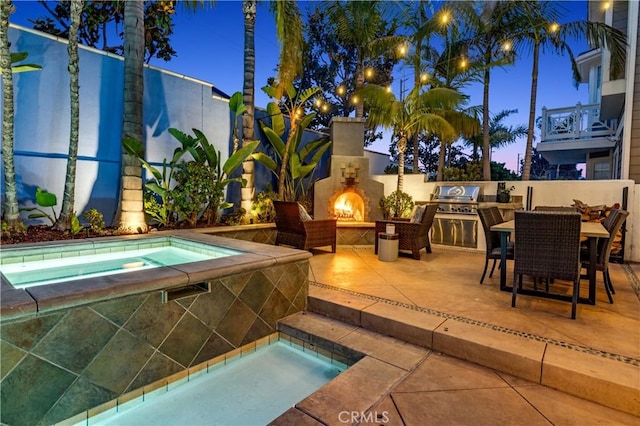 view of swimming pool featuring an in ground hot tub, area for grilling, a lit fireplace, and a patio area