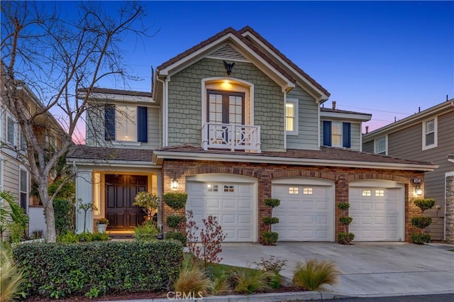 traditional-style home with a garage, concrete driveway, brick siding, and a balcony